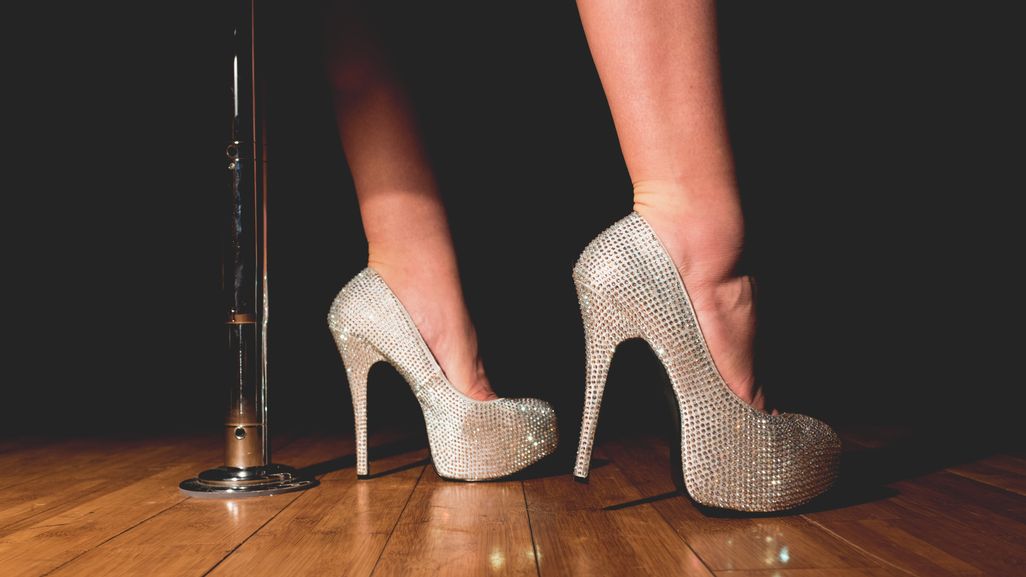 Person wearing sparkly heels standing next to a pole