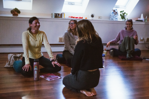 Portland-Maine-Hustle-and-Flow-Dance-Cardio-Teacher-Training-2 A woman in a sparkly black sports bra raising her right arm above her head while looking upward.